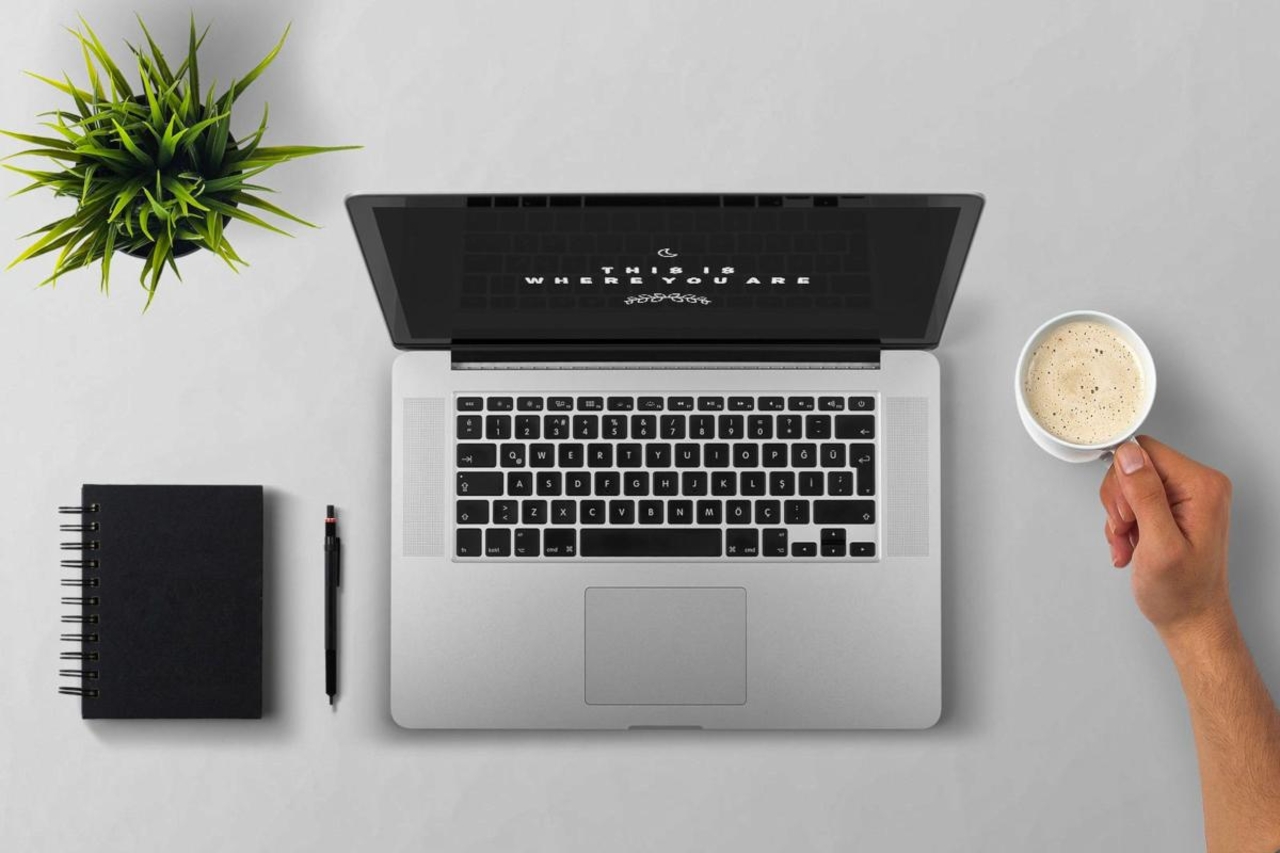 Laptop on a desk with succulent, notebook, and coffee